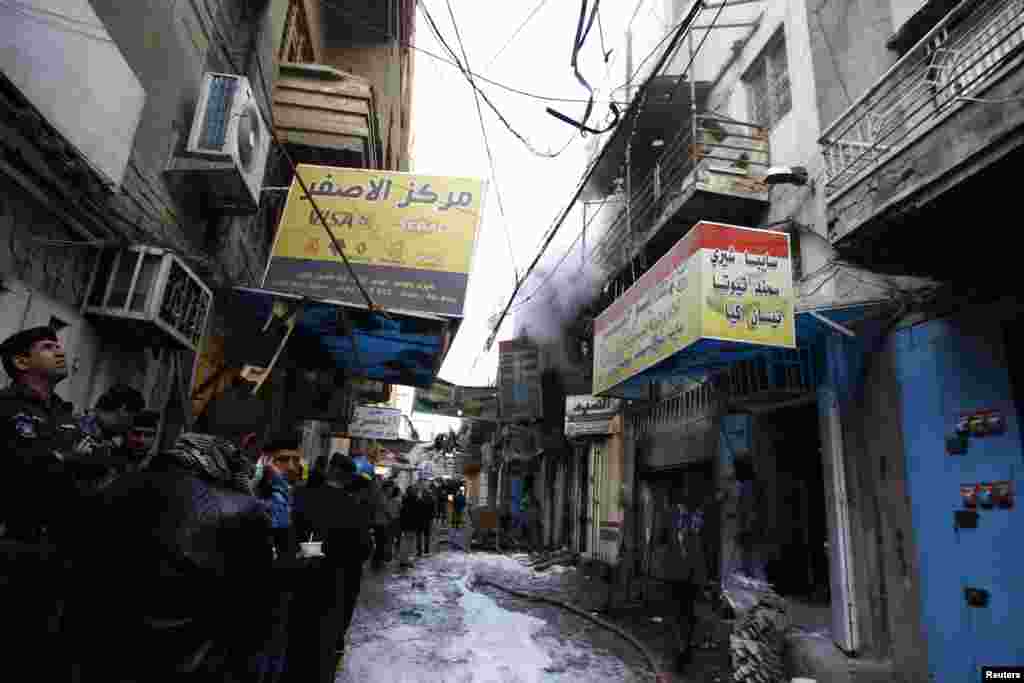 Iraqi security forces look up as smoke billows after an explosion in the business district of Sinak in central Baghdad, Feb. 5, 2014. 