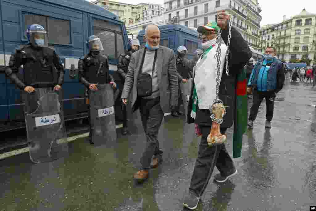 A man holds a bone while shouting &quot;That&#39;s what&#39;s left for those who vote for the President&quot; as Algerians demonstrate in Algiers to mark the second anniversary of the Hirak movement.