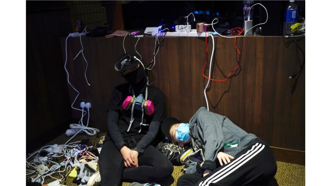 Pro-democracy protesters take a nap while charging their devices inside the campus of the Hong Kong Baptist University in Hong Kong, Nov. 13, 2019.