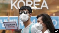 A couple wears masks as a precaution against the Middle East Respiratory Syndrome (MERS) virus as they walk in Myeongdong, one of Seoul's main shopping districts, June 15, 2015. 