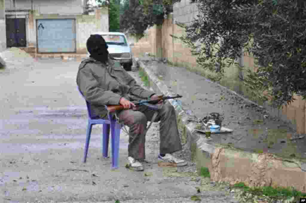 A Syrian rebel guards an alley, at Rastan area in Homs province, central Syria, on Wednesday Feb. 1, 2012.