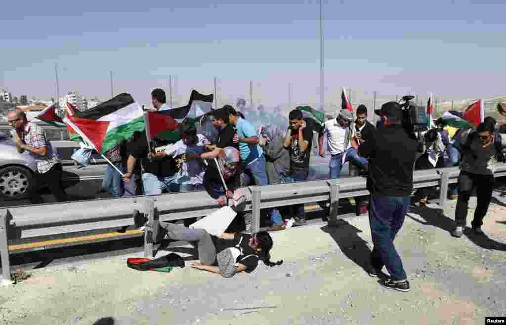 Palestinian protesters run as Israeli border policemen fire a stun grenade during a demonstration to show solidarity with Bedouin citizens, near the West Bank village of Hizma, south-east of Ramallah. Some 60 protesters demonstrated against an Israeli cabinet plan to relocate some 30,000 Bedouin citizens who live in unrecognized villages in Israel&#39;s southern Negev desert and relocate them to towns built by the government.