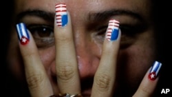 Una modelo posa mostrando sus uñas decoradas con banderas de Cuba y Estados Unidos en La Habana.