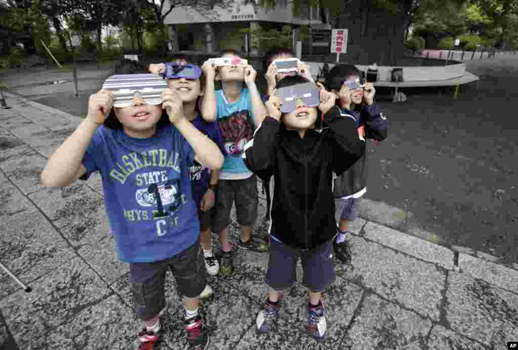 Children watch an annular solar eclipse in Fujisawa, near Tokyo, May 21, 2012. 