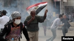 Anti-Morsi protesters run for cover during clashes with riot police at Tahrir Square in Cairo, November 27, 2012. 