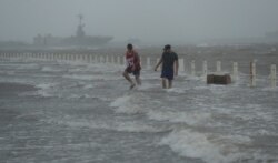 Dos hombres caminan por una calle inundada en Corpus Christi, Texas, tras la llegada del huracán Hanna, el sábado 25 de julio de 2020.