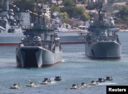 FILE - Russian armored personnel carriers submerge from amphibious assault ships during the Navy Day parade in the Black Sea port of Sevastopol, Crimea, July 26, 2020.