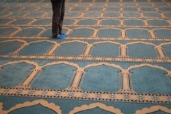 Seorang Muslim yang tinggal di Yunani mengenakan kaos kaki sebagai tindakan pencegahan terhadap penyebaran Covid-19 sebelum salat Jumat di masjid resmi pertama ibu kota, di Athena, Yunani, 6 November 2020. (Foto: REUTERS/Alkis Konstantini)