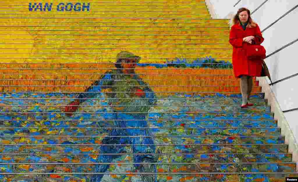 A woman walks down stairs advertising a Vincent van Gogh exhibition outside Albertina museum in Vienna.