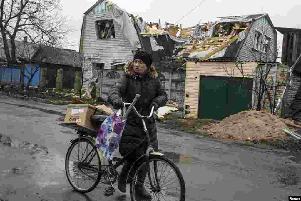 A woman pushes a bicycle past a destroyed house in the town of Debaltseve, March 13, 2015.