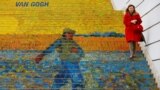 A woman walks down stairs advertising a Vincent van Gogh exhibition outside Albertina museum in Vienna.