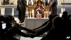 Después de encender 12 cirios, Veronica Coleman dirige a la congregación en oración durante una vigilia por Ryan Keith Cox en la Iglesia Bautista Piney Grove en Virginia Beach, Virginia, el domingo 2 de junio del 2019. (Rob Ostermaier/The Virginian-Pilot via AP)