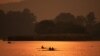 Siluet para pendayung dengan perahu mereka tampak di perairan Danau Sukhna saat matahari terbit di kota Chandigarh, India. (AFP)&nbsp;