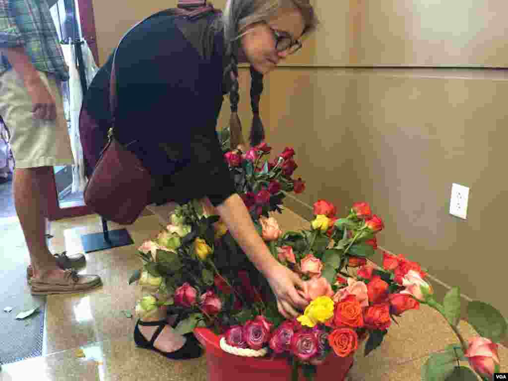 A woman places flowers along one area of the sports arena for the vigil in remembrance of the nine people who died in a shooting at Emanuel AME Church, June 19, 2015. (Amanda Scott/VOA)