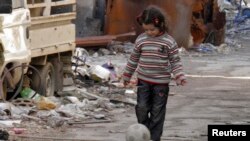 A girl plays with a ball along a street in the besieged area of Homs, January 30, 2014. 