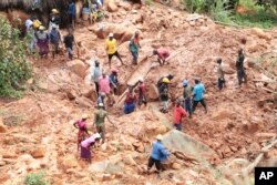 A family digs for their son who got buried in the mud when Cyclone Idai struck in Chimanimani about 600 kilometers (375 miles) southeast of Harare, Zimbabwe, March, 19, 2019.