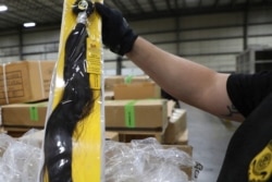 FILE - In this June 29, 2020, photo, provided by U.S. Customs and Border Protection, an officer inspects a hair accessory at an exam station in Newark, New Jersey. Some of the products are believed to be made in Chinese detention camps.