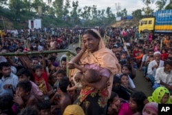 A Rohingya Muslim woman, who crossed over from Myanmar into Bangladesh, wipes her sweat as she waits to receive aid during its distribution near Balukhali refugee camp, Bangladesh, Sept. 25, 2017.