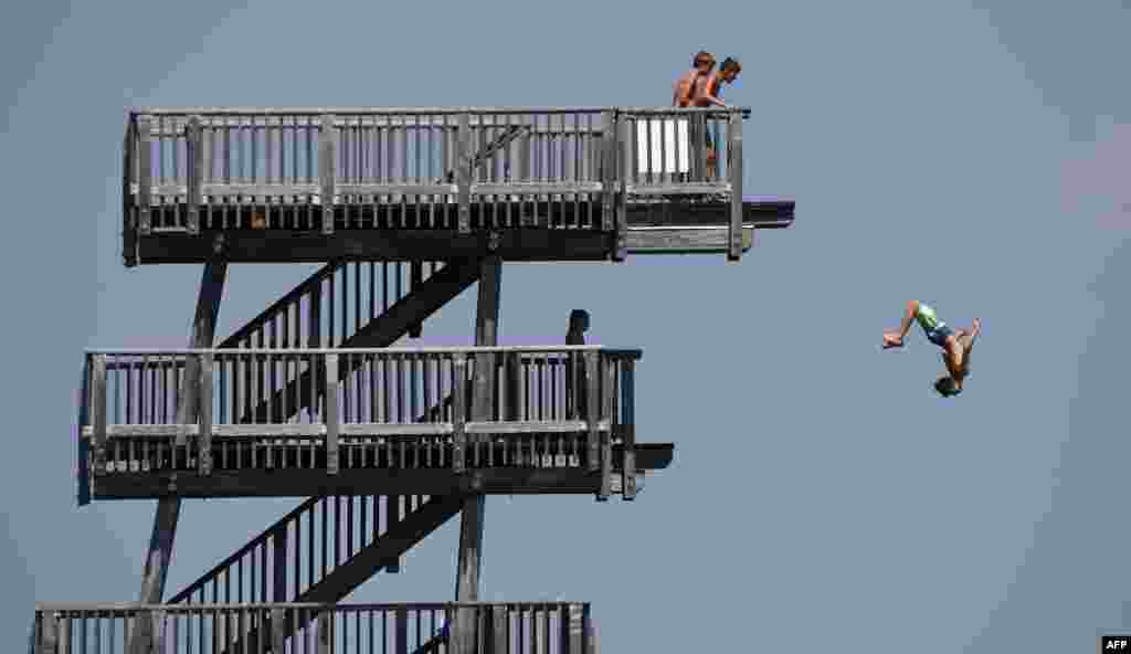 A boy jumps from a diving tower on the shore of the lake Ammersee near the small Bavarian village of Utting, southern Germany, where temperatures reached around 30 degrees celsius.