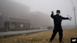 FILE - A security person moves journalists away from the Wuhan Institute of Virology after a World Health Organization team arrived for a field visit in Wuhan in China's Hubei province, Feb. 3, 2021. 