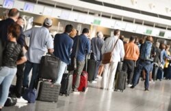 Air travellers stand in a queue in Terminal 1 of Frankfurt Airport in front of a check-in counter, Germany, June 15, 2020.