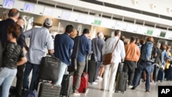 FILE - Air travelers stand in a queue in Terminal 1 of Frankfurt Airport, Germany, in front of a check-in counter, June 15, 2020.