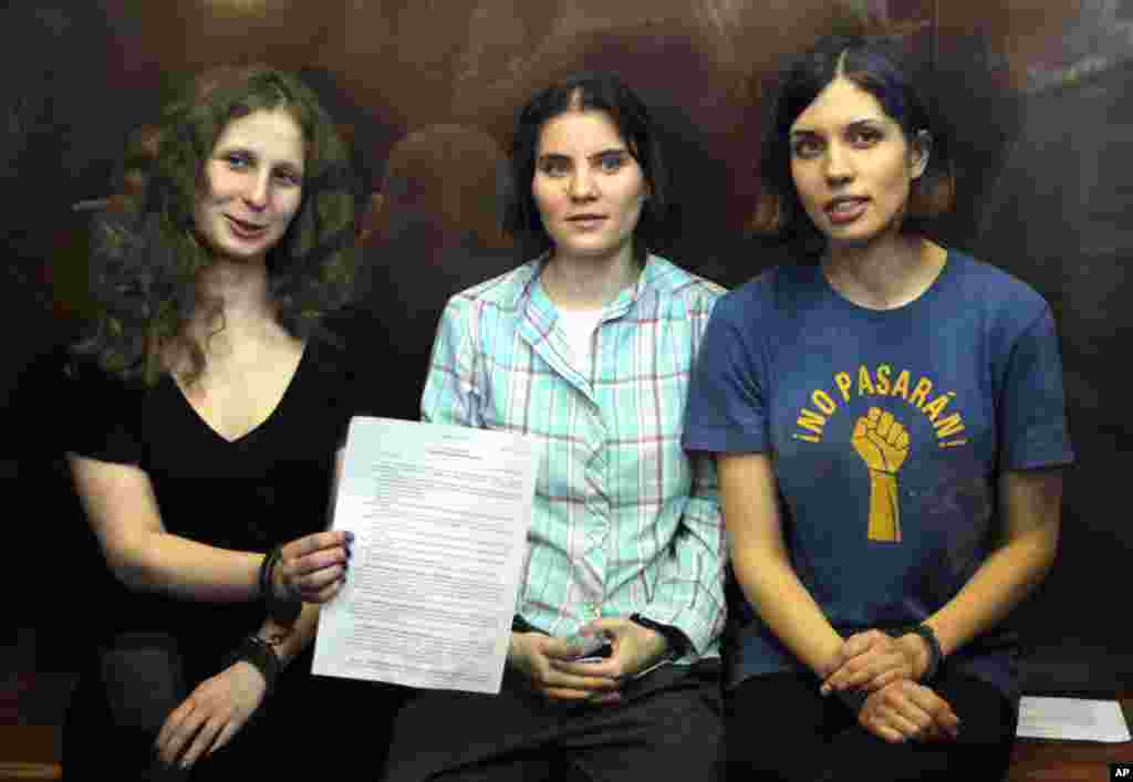 Pussy Riot members, from left, Maria Alekhina, Yekaterina Samutsevich, and Nadezhda Tolokonnikova show the court&#39;s verdict as they sit in a glass cage at a courtroom in Moscow, August 17, 2012.