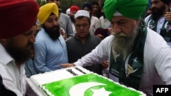پاکستان کے شہر پشاور میں سکھ مذہب کے پیروکار 14 اگست 2017ء کو یومِ آزادی کے موقع کیک لے جارہے ہیں جس پر پاکستانی پرچم بنا ہوا ہے (فائل فوٹو)