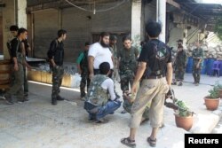 FILE - Free Syrian Army fighters carry their weapons as they gather for what they said was an operation to travel to the northern countryside of Aleppo to fight Islamic State fighters, in Aleppo, Syria.