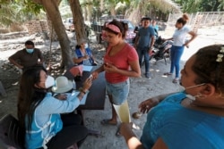 An activist from the ruling Partido Nacional (National Party) holds the identification of a woman to register on a list to receive help from the government for the people affected by the floods caused by hurricanes Eta and Iota, in El Progreso, Honduras.