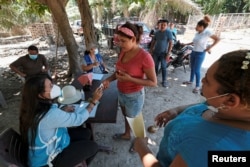 An activist from the ruling Partido Nacional (National Party) holds the identification of a woman to register on a list to receive help from the government for the people affected by the floods caused by hurricanes Eta and Iota, in El Progreso, Honduras.