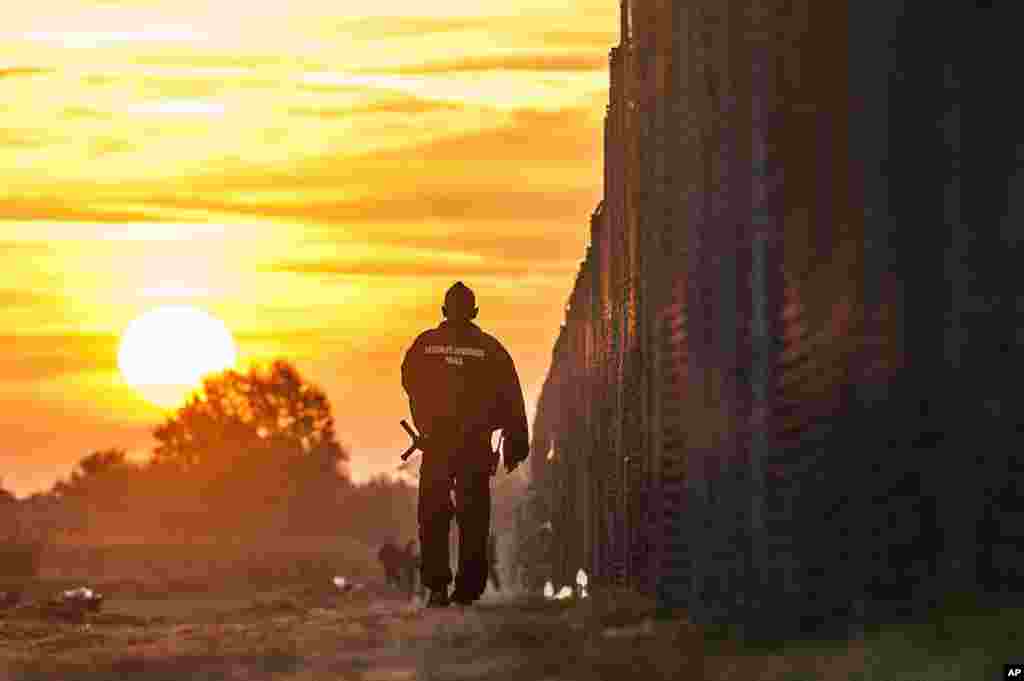 A Hungarian police officer patrols along the temporary border fence on the Hungarian-Serbian border near Roszke, 180 kms southeast of Budapest, Hungary, during sunrise one day after Hungary closed its border to Serbia.