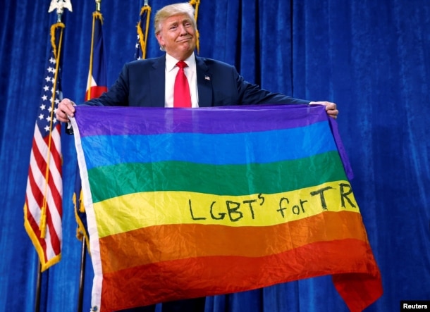 Then-Republican presidential nominee Donald Trump holds up a rainbow flag with "LGBTs for TRUMP" written on it at a campaign rally in Greeley, Colo., Oct. 30, 2016.