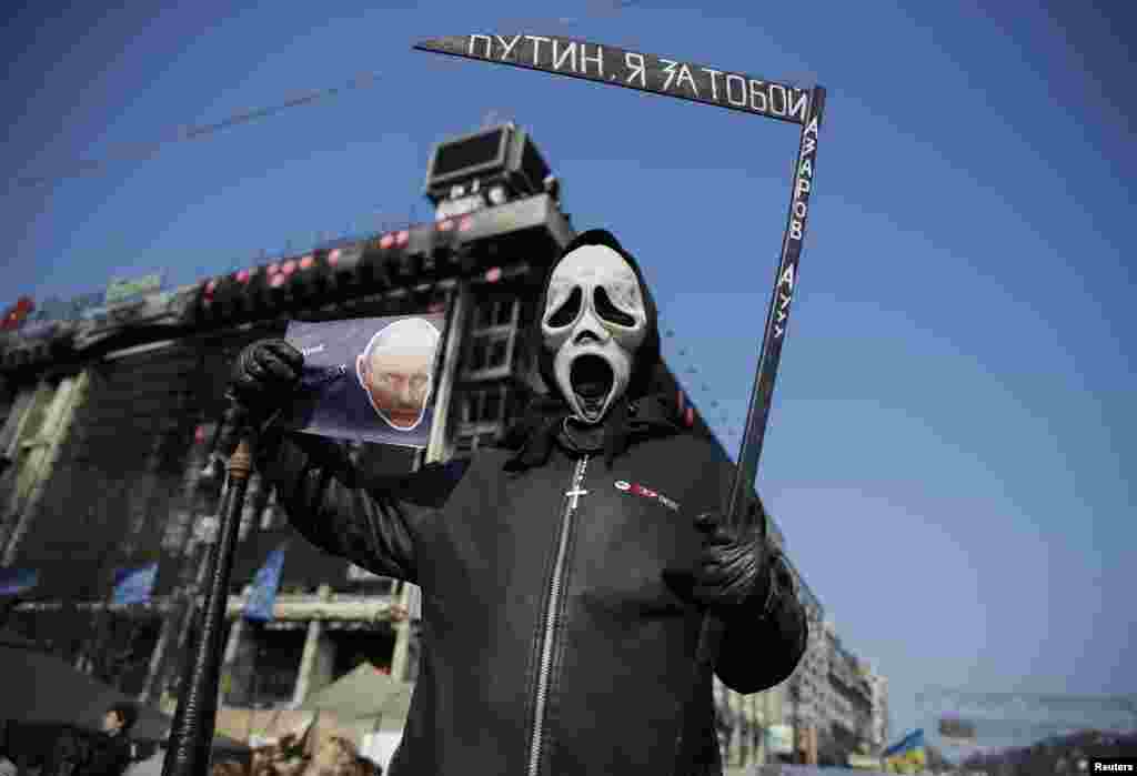 A protester holds a sign depicting Russian President Vladimir Putin as he attends an anti-war rally in Independence Square in Kyiv, March 23, 2014. 