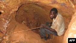 FILE - A man sits in a hole he dug in the rock with makeshif tools in search for gold at the Soedoumbofor site near the eastern Cameroonian town of Batouri, June 1, 2008.
