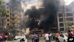 FILE - People watch after a Kurdish rebel suicide bomber detonated an explosives-laden vehicle outside a police headquarters in Midyat, near Turkey's border with Syria, June 8, 2016.