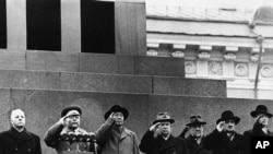 1957年11月11日毛泽东在莫斯科红场(左三)与苏联最高领导人站在列宁墓前敬礼。左起为苏联国家元首德米特里·伏罗希洛夫；国防部长罗季翁·马利诺夫斯基元帅，毛泽东；苏联共产党主席尼基塔·赫鲁晓夫；总理尼古拉·布尔加宁；副总理阿纳斯塔斯·米高扬；和执政主席团成员苏斯洛夫
