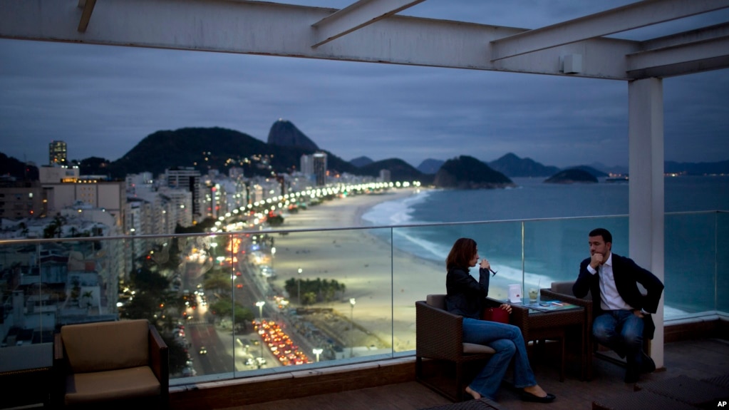 FILE - Tourists sit in a bar at a hotel overlooking Copacabana beach, in Rio de Janeiro, Brazil, Aug. 16, 2013.