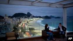 FILE - Tourists sit in a bar at a hotel overlooking Copacabana beach, in Rio de Janeiro, Brazil, Aug. 16, 2013.