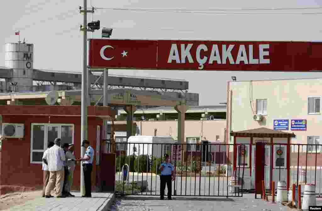 在阿克恰卡莱通关口，一名土耳其警察查看从叙利亚入境土耳其的叙利亚男子的身份证。（2012年10月4日）
