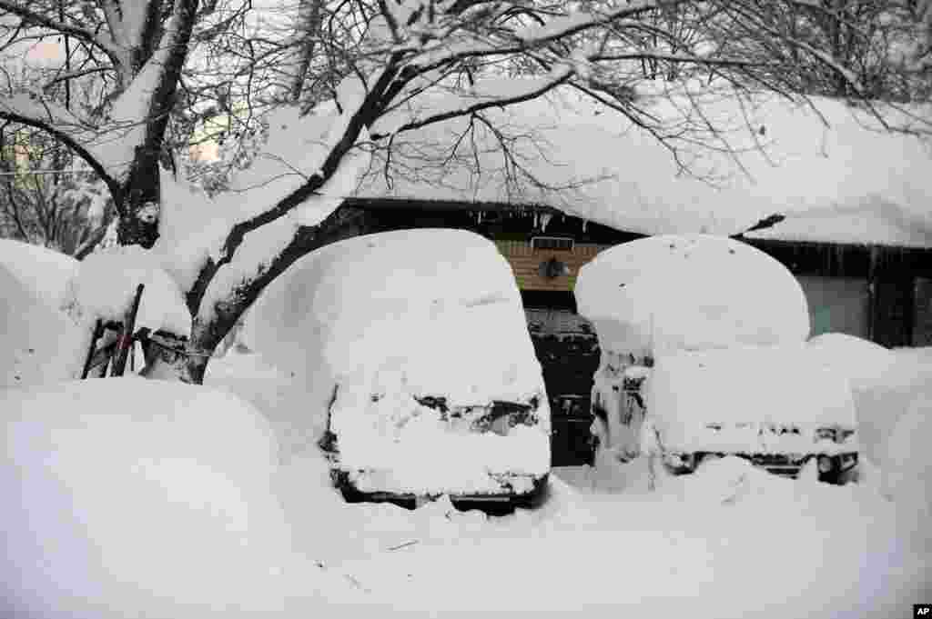 Des véhicules couverts d&rsquo;épaisse couche de neige dans une rue de la région sud Buffalo, jeudi 20 novembre 2014, à Buffalo, NY.