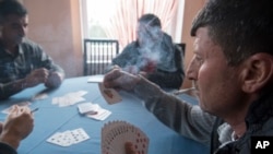 FILE - Refugees from the Yazidi community play cards inside a hotel in the northern Greek village of Agios Athanasios, Dec. 21, 2016. Portugal has offered to take in several hundred of the 2,500 Yazidi refugees living in Greece, arguing that the mistreated religious minority merits special protection.