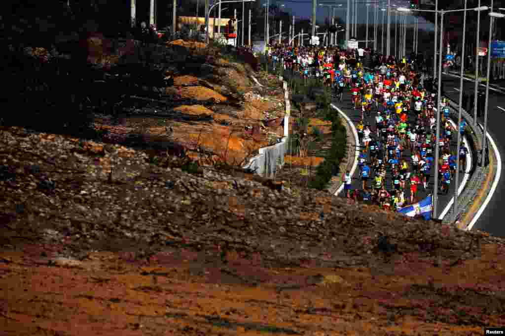 Runners race past a hill burned in Greece&#39;s deadliest wildfire in July, during the 36th Athens Classic Marathon, in the village of Mati, near Athens, Nov. 11, 2018.