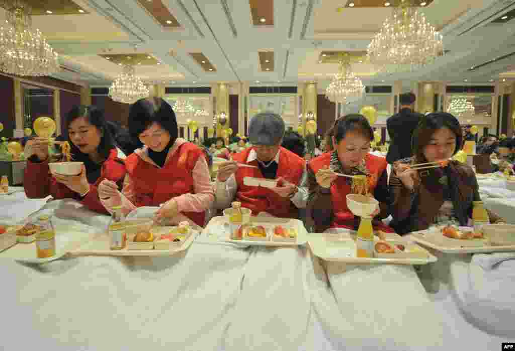 Những người tham gia một sự kiện nhằm mục đích phá vỡ kỷ lục thế giới về số lượng người ăn sáng trên giường đông nhất trong một phòng khiêu vũ ở Thượng Hải.