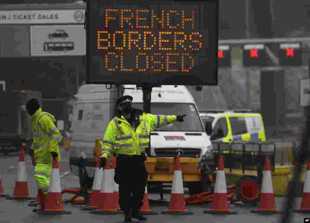 A police officer directs traffic at the entrance to the closed ferry terminal in Dover, England, after the Port of Dover was closed and access to the Eurotunnel terminal suspended following the French government&#39;s announcement.&nbsp;France banned all travel from the UK for 48 hours from midnight Sunday due to a new coronavirus strain.