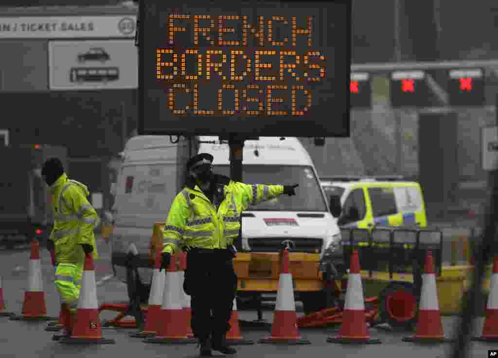 A police officer directs traffic at the entrance to the closed ferry terminal in Dover, England, after the Port of Dover was closed and use of the Eurotunnel terminal suspended following the French government's announcement. France banned all travel from Britain for 48 hours from midnight Sunday because of a new coronavirus strain.