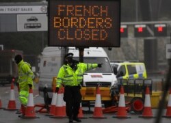 Seorang polisi mengarahkan lalu lintas di pintu masuk terminal feri di Dover, Inggris, yang dinyatakan ditutup, Senin, 21 Desember 2020.