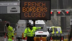 A police officer directs traffic at the entrance to the closed ferry terminal in Dover, England, Monday, Dec. 21, 2020, after the Port of Dover was closed and access to the Eurotunnel terminal suspended following the French government's announcement. Fran