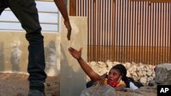 Migrantes haitianos intenta cruzar por una brecha en el muro fronterizo para llegar a Estados Unidos luego de cruzar desde México en Yuma, Arizona, el 10 de junio de 2021.