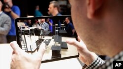 A man looks at an iPad in the display room at the Apple Worldwide Developers Conference in San Jose, Calif., Monday, June 3, 2019. (AP Photo/Jeff Chiu)